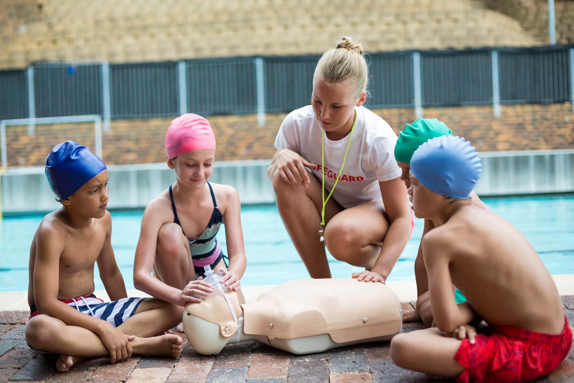 Lifeguard instructing children on essential water safety tips at a swimming pool.